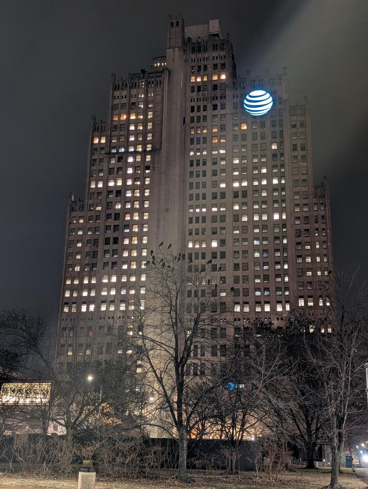 A tall art deco tower in downtown St. Louis lit at night