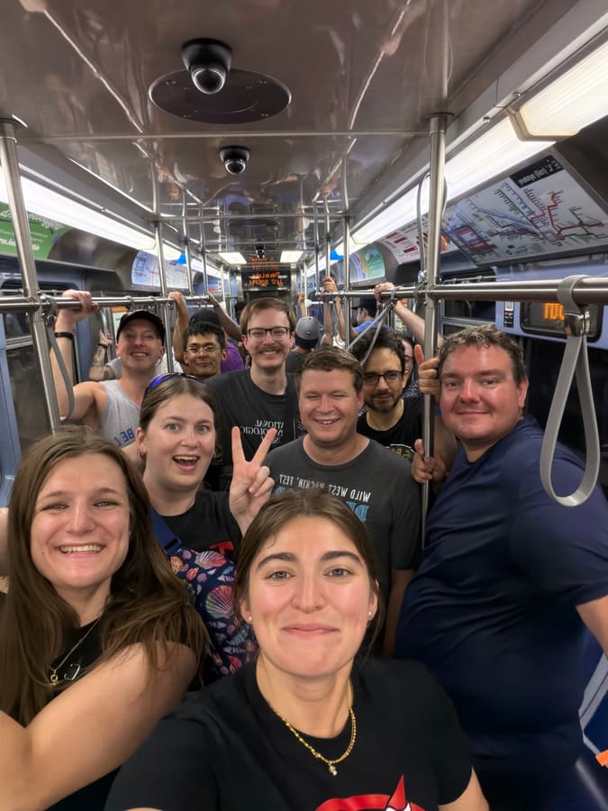 A selfie packed with Hobocon attendees standing in a CTA L car holding the grab rails, the system map and destination display visible overhead